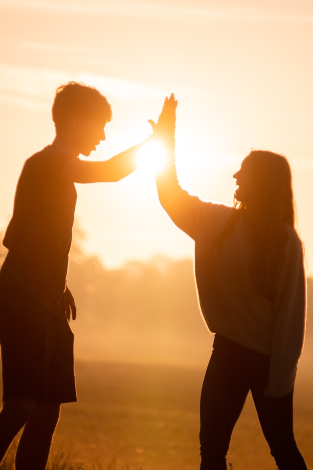 “Silhouetted parent and child giving a high-five at sunset, symbolising confidence and celebration of progress in learning multiplication at James An College Eastwood.”