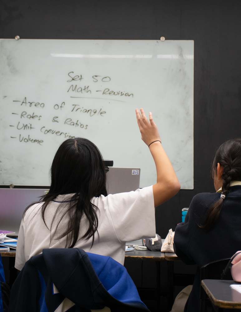 Is Your Child Missing the Point in Exams? How to Help Them Answer Questions Effectively “Student actively avoiding the Topic Trap by asking questions during a focused maths revision class.”